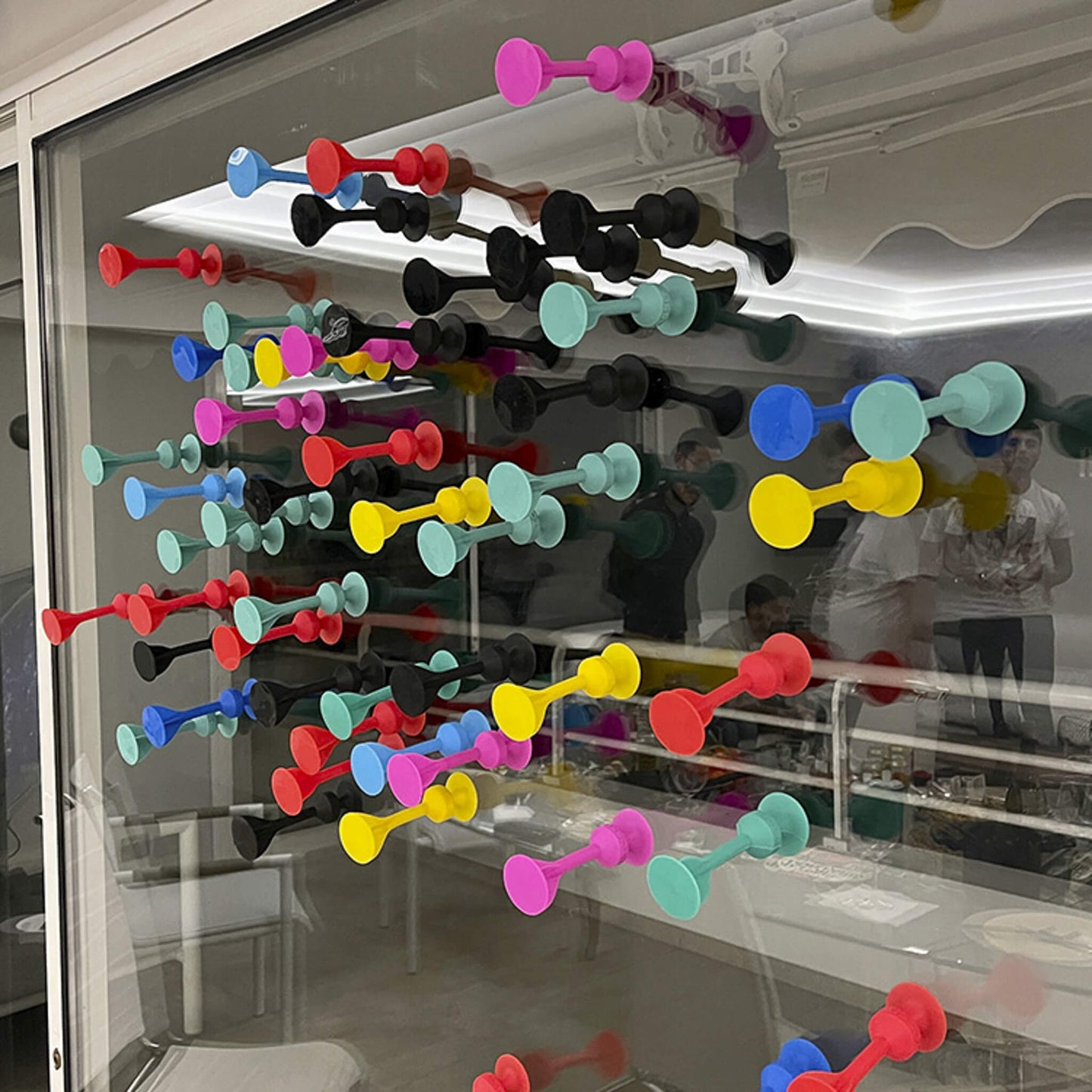 TOSSIT Dartpfeile, die an ein Fenster geklebt werden und alle Farben zeigen.